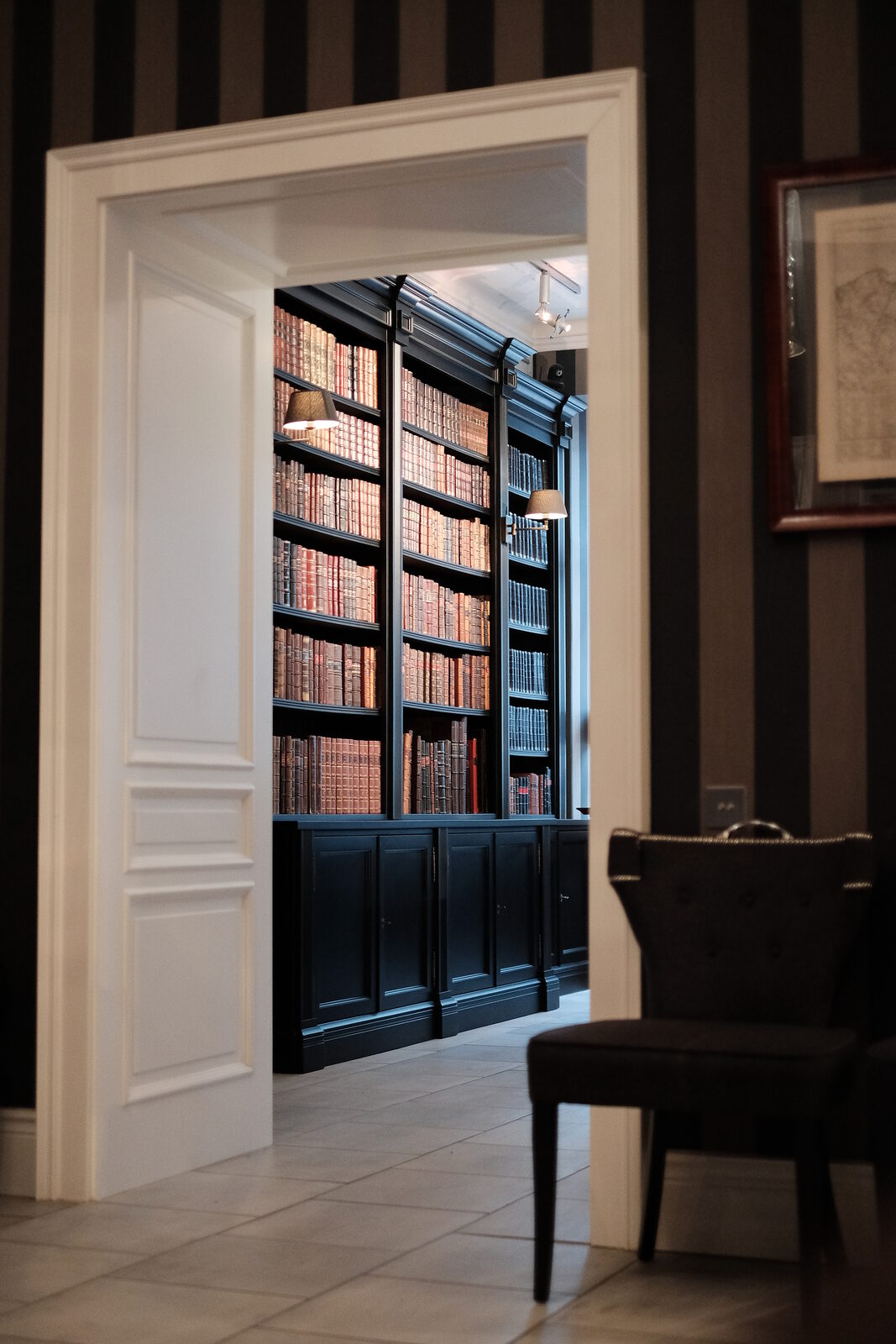 View through white doors into the bookshop, with tall black bookcases full of old books