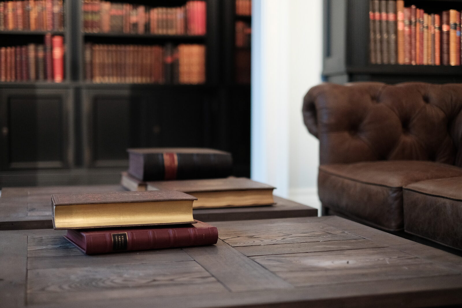 Leather-bound books on an oak table at Antykwariat Polski, with antique bookcases behind them